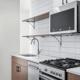 Elevate your living experience with sleek stainless steel appliances in every unit at Teller House. a kitchen with white tiling.